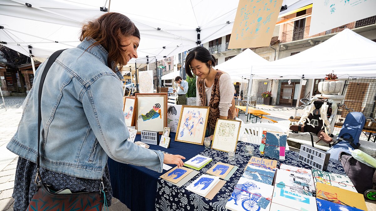 nella foto: visitatrice ad un banco di libri della mostra mercato di illustrazione e artigianato creativo | Imaginé