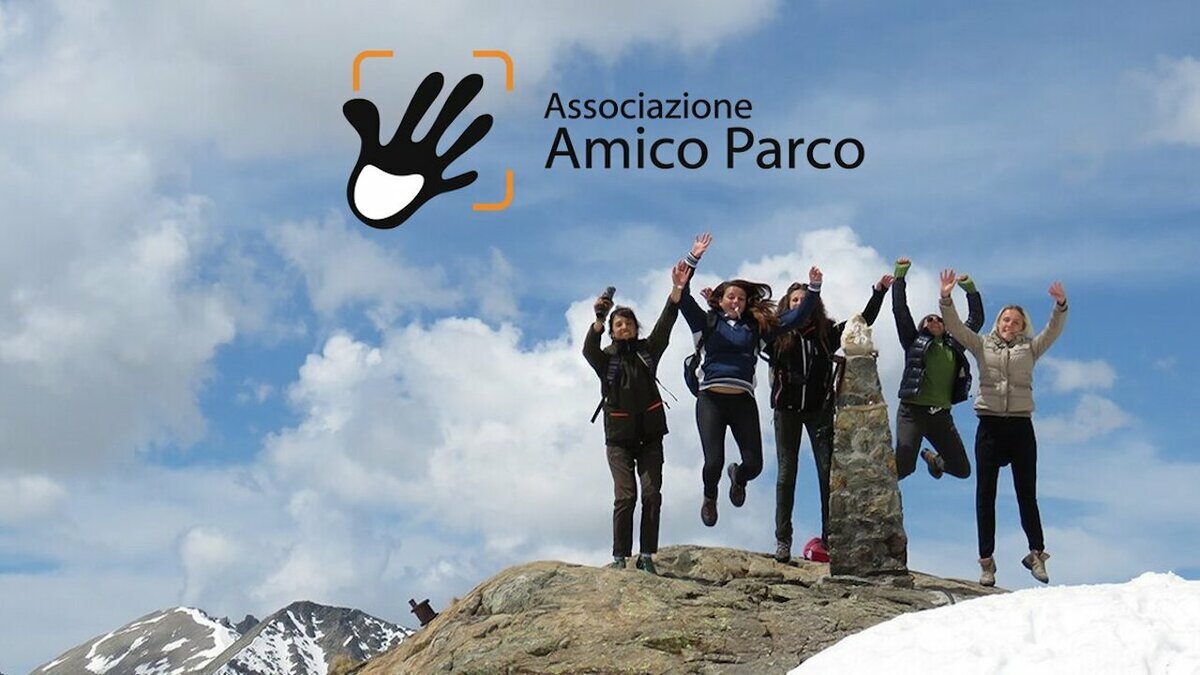 Fotografia di cinque giovani che, arrivate su una cima, esultano. Sullo sfondo il cielo azzurro e qualche nuvola bianca. E' stata aggiunta il logo e la scritta Associazione Amico Parco. Il simbolo del logo è una mano aperta. | Scattata da A. Rivelli