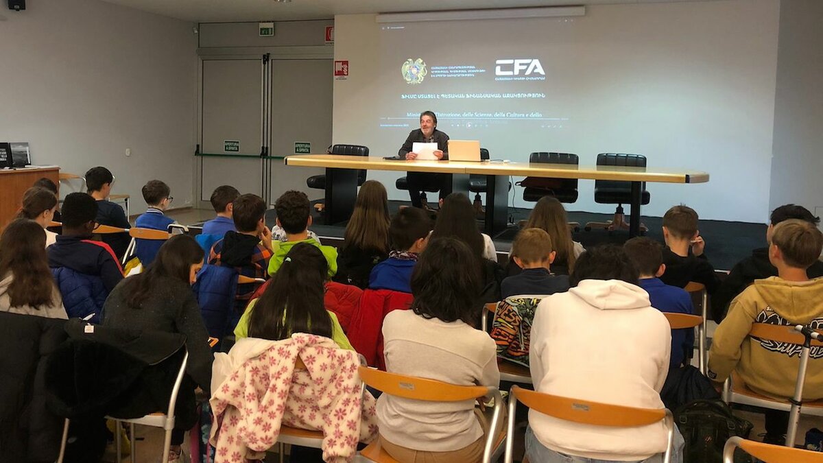 La foto, scattata da Erika Chiecchio, mostra un gruppo di studenti dell'Istituto comprensivo di Chiusa di Pesio e Peveragno, visti di spalle, seduti su delle sedie all'interno della sala incontri R. Mucciarelli di Chiusa Pesio, pronti a votare i film vincitori dell'EcoFestiValPesio. Sull sfondo, rivolto verso di noi su un piccolo palzo in posizione sopraelevata rispetto agli studenti, si vede G. Baudena, l'organizzatore del Festival. Alle sue spalle lo schermo del proiettore. Fine della descrizione.