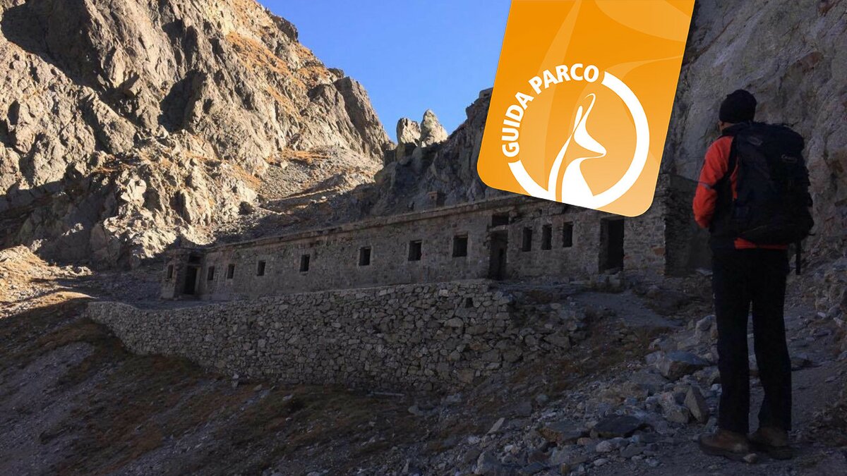 Lo scatto di E. Resta mostra il Colle di Finestra. A destra una persona di spalle, sopra il logo arancione delle escursioni con la Guida Parco. Fine della descrizione.