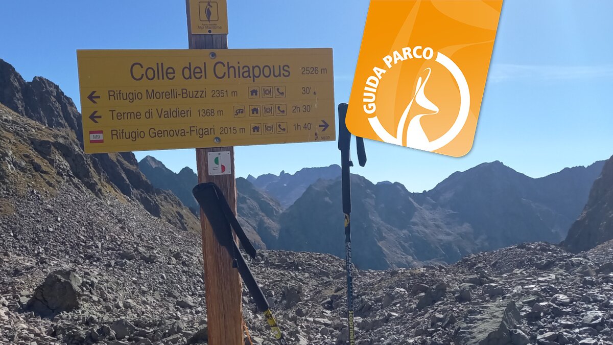 Lo scatto di E. Resta mostra il cartello che indica la direzione per il Colle del Chiapous. In alto a destra in arancione il logo per le escursioni con la Guida Parco. Fine della descrizione.