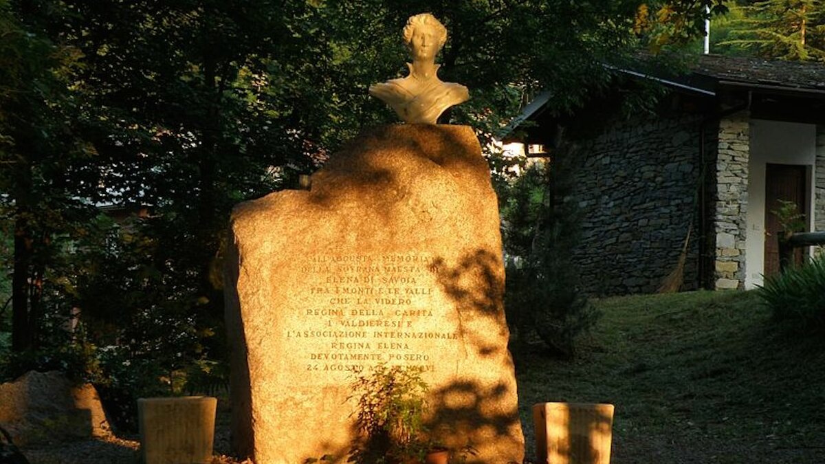 Lo scatto di A. Rivelli mostra il monumento alla Regina Elena illuminato all'alba, sito nella piazza di Sant'Anna di Valdieri. Fine della descrizione.