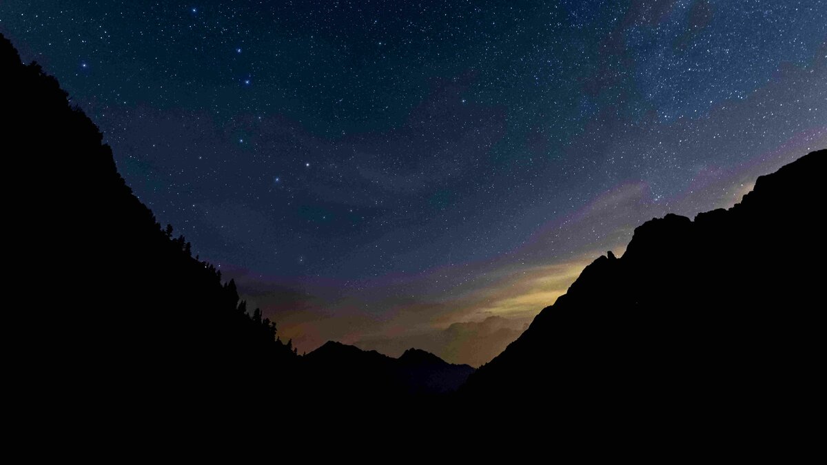 Panorama notturno dal bivacco Varrone: l'alone arancione ai piedi delle montagne è dovuto all' inquinamento luminoso. Fine didascalia.