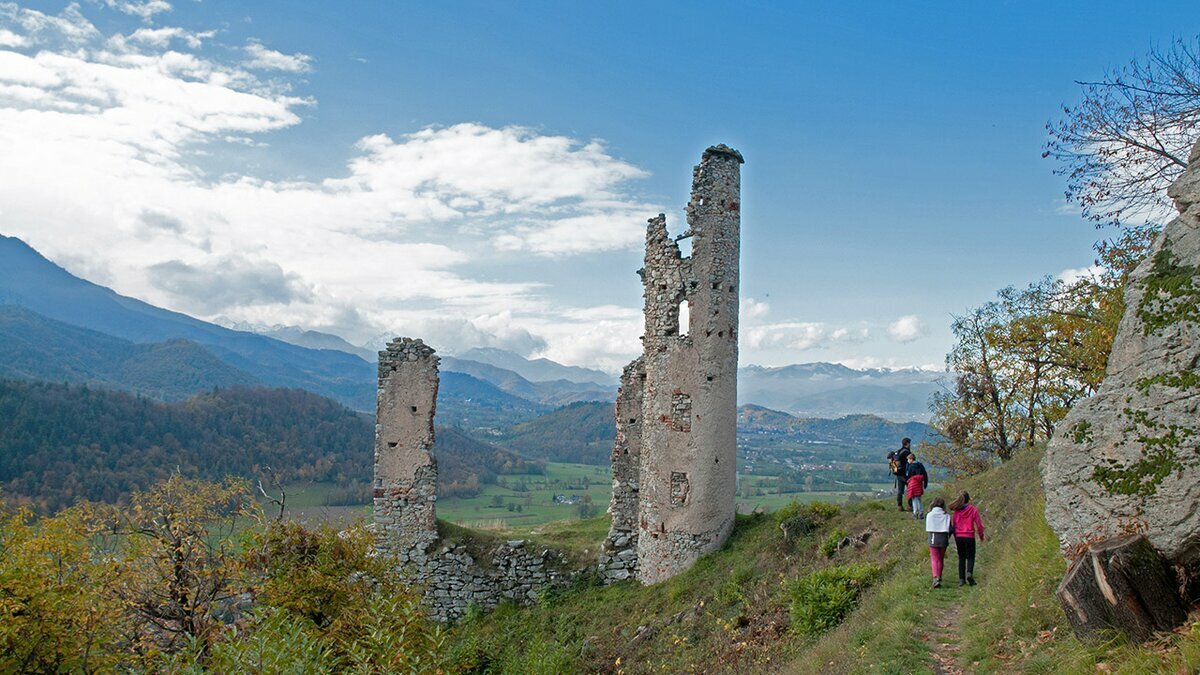 Lo scatto di G. Bernardi mostra, al centro e sulla sinistra, i ruderi del Castello di Mirabello. Sulla strada sulla destra alcuni escursionisti in cammino. Fine della descrizione.