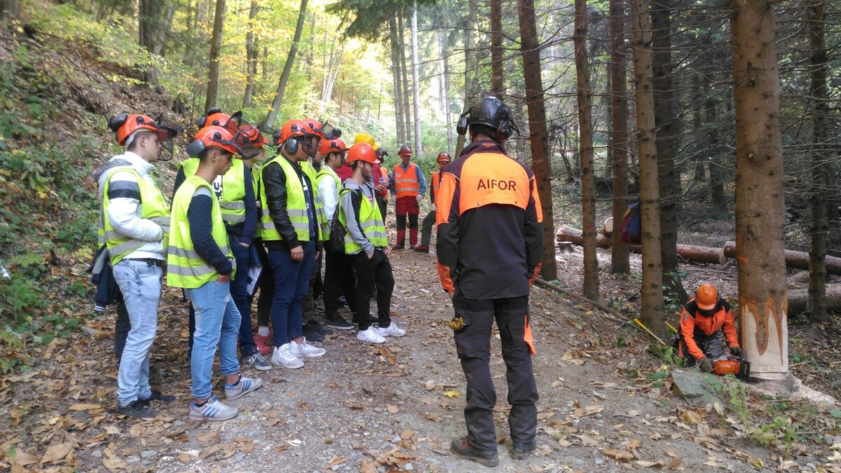 Lo scatto mostra sulla sinistra un gruppo di ragazzi che stanno ascoltando la formazione tenuta dagli Istruttori Forestali. Si trovano in un bosco, nel Parco del Marguareis. Fine della descrizione.