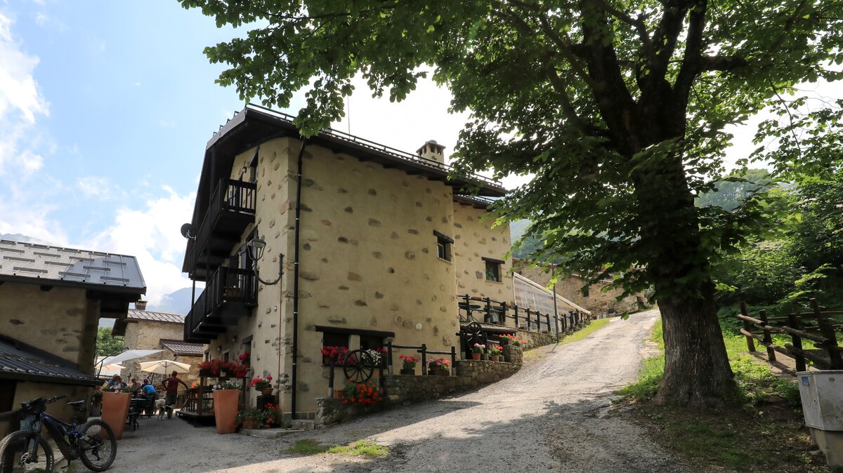 Nella foto L'Arbergh a Palanfrè con i gerani rossi, una bici in primo piano e clienti nel dehor| G. Bernardi Fine descrizione foto.