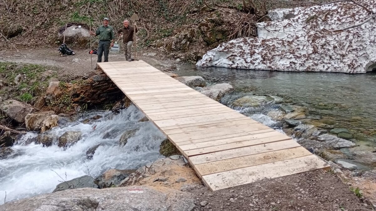 Nella foto di vede la nuova passerella sul rio del Saut con due addetti che hanno lavorato al ripristino | APAM Fine descrizione foto.