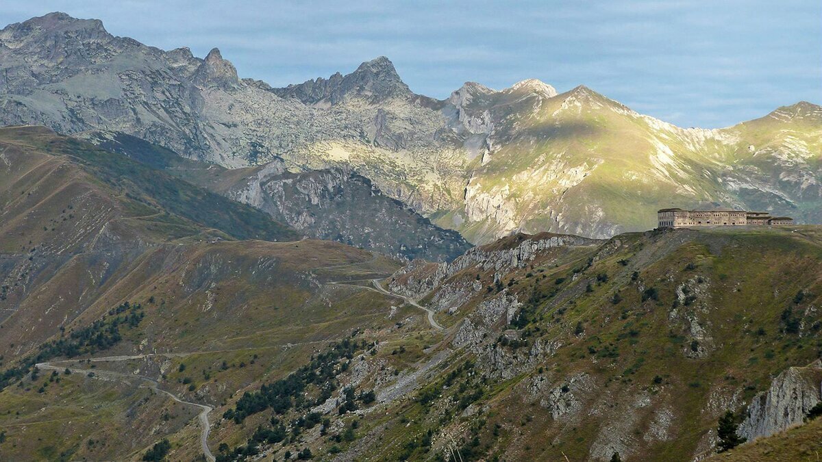 Panoramica del Colle di Tenda, luogo simbolo di incontro tra Italia e Francia, con le storiche fortificazioni sul crinale e le vette alpine sullo sfondo. Fine descrizione della fotografia.