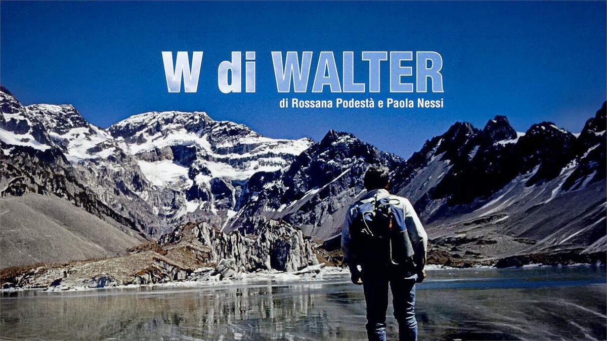 Copertina del film W di Walter: Walter Bonatti, visto di spalle con lo zaino, osserva un vasto paesaggio dominato da un ghiacciaio, cime innevate e un lago di montagna che riflette il cielo. Fine descrizione della fotografia.